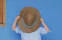 Хлопчик вкриває обличчя сонячним капелюхом — стокове фото