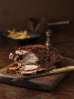 Carved roasted lamb on kitchen table with french fries — Stock Photo