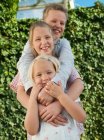 Niño y dos hermanas sonriendo, retrato - foto de stock