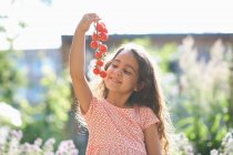 Retrato de niña sosteniendo un montón de tomates cherry en el jardín - foto de stock