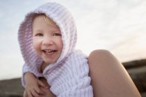 Portrait of female toddler between fathers legs on beach — Stock Photo