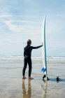 Rapaz a olhar para o mar com prancha de surf — Fotografia de Stock
