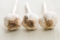 Tre bulbi di aglio in fila — Foto stock