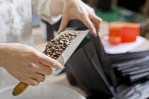 Coffee seller filling bag with coffee beans — Stock Photo