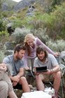 Група молодих туристів роблять перерву, дивлячись на тримається за руку комп'ютер — стокове фото