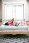 Porträt eines Mädchens, das mit Mutter und Schwester im Bett herumalbert — Stockfoto