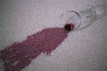 Vidrio con mancha de vino tinto en una alfombra - foto de stock