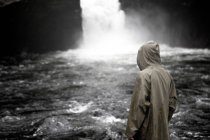 Rear view of person with obscured face standing near waterfall — Stock Photo