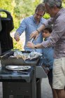Famille de trois générations préparant la nourriture sur barbecue — Photo de stock