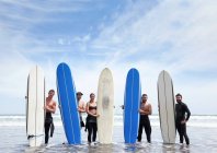 Gruppenporträt von männlichen und weiblichen Surferfreunden, die mit Surfbrettern im Meer stehen — Stockfoto