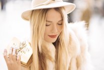 Stylish young woman holding gold jewelry box, Covent Garden, London, UK — Stock Photo
