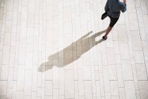 Empresaria corriendo sobre pavimento a la luz del sol - foto de stock