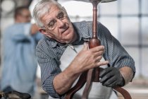 Cape Town, South Africa, elderly craftsman adjusting wooden arm in workshop — Stock Photo