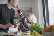 Boy touching father face in kitchen at home — Stock Photo