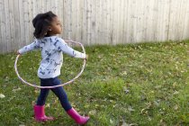 Милая девушка играет в саду с пластиковым обручем — стоковое фото