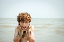 Boy playing with wet sand on beach — Stock Photo