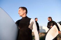 Three surfers at beach — Stock Photo