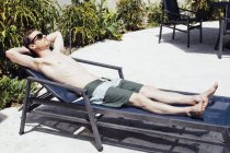 Hombre adulto medio tomando el sol en una tumbona, Miami Beach, Florida, EE.UU. - foto de stock