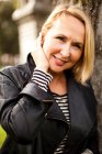 Mature woman wearing leather jacket and smiling in park, portrait — Stock Photo