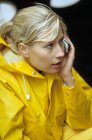 Frau in gelbem Regenmantel benutzt Handy — Stockfoto