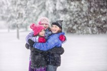 Freunde umarmen sich bei Schneefall — Stockfoto
