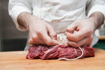Açougueiro amarrando lombo de carne com corda — Fotografia de Stock
