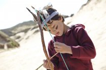 Jeune garçon vêtu d'une robe fantaisie, tenant arc et flèche faits maison — Photo de stock