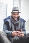 Uomo d'affari sorridente seduto sulle scale e utilizzando smartphone — Foto stock
