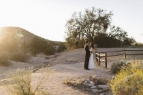 Bride and groom, in arid landscape, standing face to face — Stock Photo