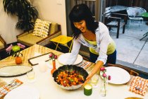 Femme plaçant le plat sur la table à manger — Photo de stock