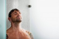 Mann wäscht sich unter der Dusche die Haare — Stockfoto
