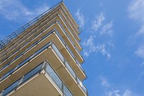 Edificio de apartamentos con balcones bajo cielo azul nublado - foto de stock