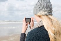 Mujer junto al mar con cámara - foto de stock