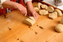 Image recadrée de la femme âgée tranchant la pâte sur la planche à découper — Photo de stock