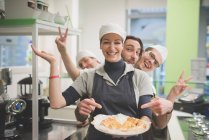 Waitress carrying plate of food, colleagues making fun behind — Stock Photo