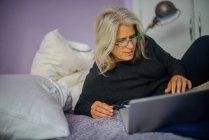 Mujer usando portátil en la cama - foto de stock