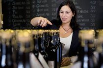 Жінка рахує пляшки вина в магазині — стокове фото