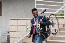 Young man carrying bicycle down steps — Stock Photo