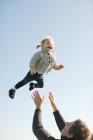 Kleinkind von Vater gegen blauen Himmel geschleudert — Stockfoto