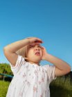 Young girl shielding eyes outside — Stock Photo