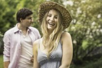 Young woman wearing straw hat laughing, portrait — Stock Photo