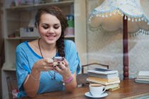 Jeune femme dans un café en utilisant un téléphone portable — Photo de stock