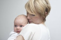 Mother carrying baby girl against chest — Stock Photo