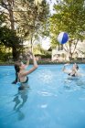 Две девочки-подростки играют с пляжным мячом в бассейне — стоковое фото