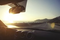 Jovem mulher na estrada que conduz a estrada da costa pacífica ao pôr do sol, Califórnia, EUA — Fotografia de Stock