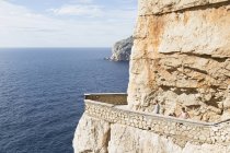 Blick aus der Vogelperspektive auf junge Männer am Meer auf Balkon, in Felsen gehauen, Grotta di nettuno (Neptungrotte), Capo caccia, Sardinien, Italien — Stockfoto