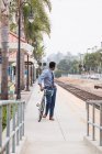 Молодой бизнесмен велосипедист, оглядываясь назад с железнодорожной станции платформы — стоковое фото