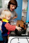 Mother and son making porridge in kitchen — Stock Photo