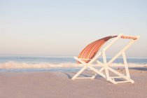 Шезлонги на пляжі з смугастим текстилем, що пробивається на вітрі — стокове фото