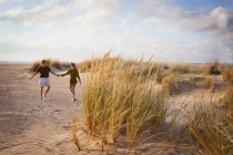 Середня доросла пара тримає руки на пляжі — стокове фото